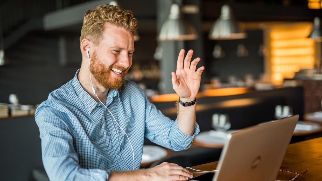 Happy young businessman waving to an online client.