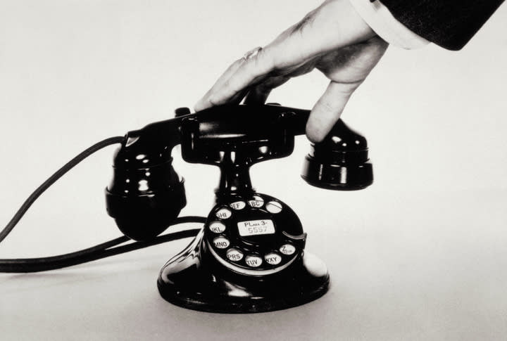 Person's hand hanging up an old-fashioned rotary telephone