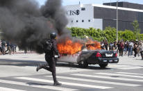 A person runs while a police vehicle is burning during a protest over the death of George Floyd in Los Angeles, Saturday, May 30, 2020. Protests across the country have escalated over the death of George Floyd who died after being restrained by Minneapolis police officers on Memorial Day, May 25. (AP Photo/Ringo H.W. Chiu)