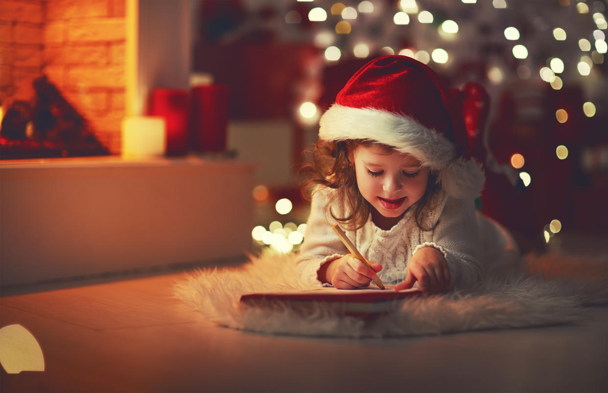 child girl writing letter santa home near the Christmas tree