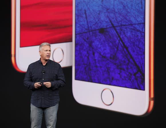 Apple executive Phil Schiller on stage with the iPhone 8 and iPhone 8 Plus projected on the screen behind him.