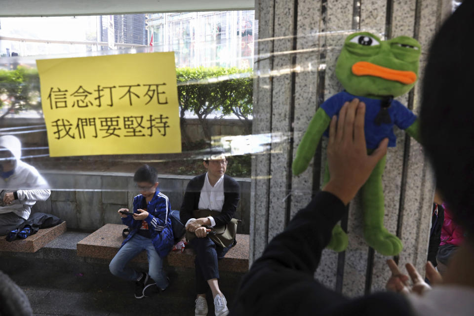 A protestor holds a stuffed frog doll near a note reading "You cannot kill beliefs, we will persevere" on a Lennon wall during a rally for students and elderly pro-democracy demonstrators in Hong Kong, Saturday, Nov. 30, 2019. Hundreds of Hong Kong pro-democracy activists rallied Friday outside the British Consulate, urging the city's former colonial ruler to emulate the U.S. and take concrete actions to support their cause, as police ended a blockade of a university campus after 12 days. (AP Photo/Ng Han Guan)