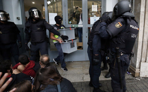 Spanish police seize ballot boxes in a polling station in Barcelona - Credit: AFP PHOTO / PAU BARRENA