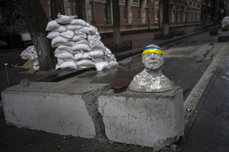 FILE - A sculpture with a headband with the flag of Ukraine is seen in a check point in Kyiv, Ukraine, on March 26, 2022. With its aspirations for a quick victory dashed by a stiff Ukrainian resistance, Russia has increasingly focused on grinding down Ukraine’s military in the east in the hope of forcing Kyiv into surrendering part of the country’s eastern territory to end the war. If Russia succeeds in encircling and destroying the Ukrainian forces in Donbas, the country’s industrial heartland, it could try to dictate its terms to Kyiv -- and possibly attempt to split the country in two.(AP Photo/Rodrigo Abd)