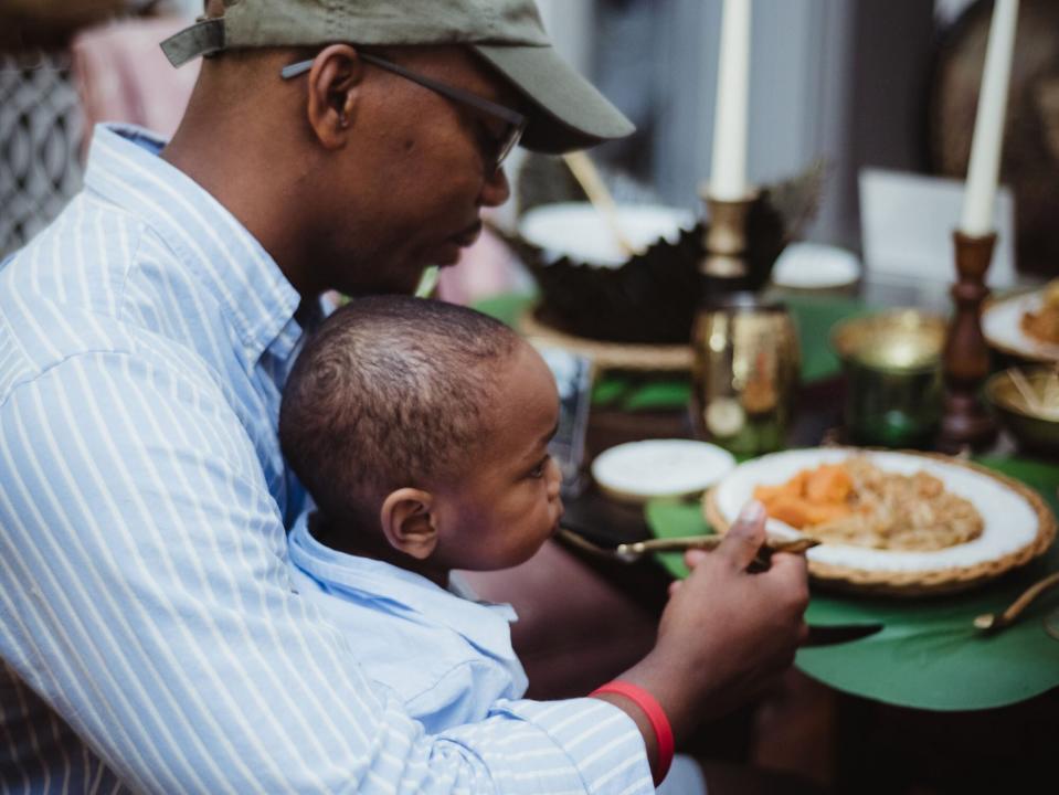 Photo of a child sitting on a man's lap at a Juneteenth celebration meal