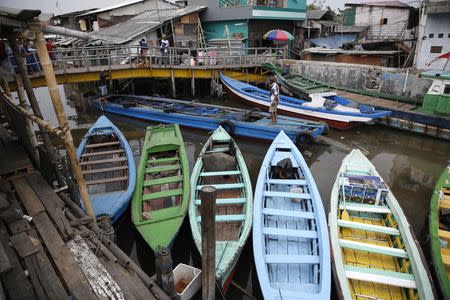 A boat passes under a bridge next to the seawall protecting Luar Batang, one of the oldest kampongs in Jakarta, dating back to the16th century, in north Jakarta in this October 7, 2014 file photo. REUTERS/Darren Whiteside/Files