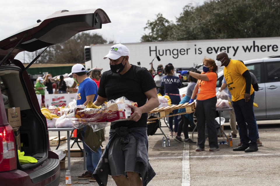 Houston Food Bank employee Enrique Albi approaches a vehicle to load food during a food distribution event in the aftermath of frigid temperatures that left the Houston area depleted of resources, Sunday, Feb. 21, 2021, in Houston. (Marie D. De Jesús/Houston Chronicle via AP)