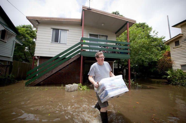 Local resident walks through floodwaters carrying some belongings, outside his Cullen Street home, in the inner Brisbane suburb of Newmarket on January 28, 2013. Helicopters have plucked dozens of stranded Australians to safety in dramatic rooftop rescues as severe floods swept the northeast, killing four people and inundating thousands of homes