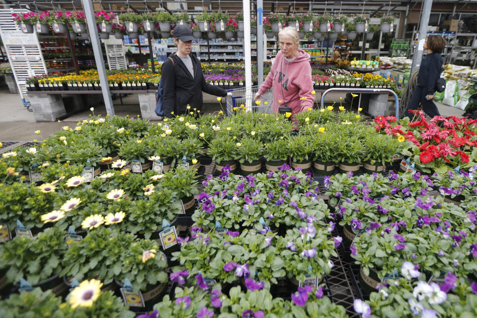 Gail Henrickson, right, and her daughter, Melissa, shop for plants at a local garden center as they stay at home during the coronavirus outbreak Monday March 23 , 2020, in Richmond, Va. The two work at a local restaurant that has closed down and are doing their spring gardening. (AP Photo/Steve Helber)