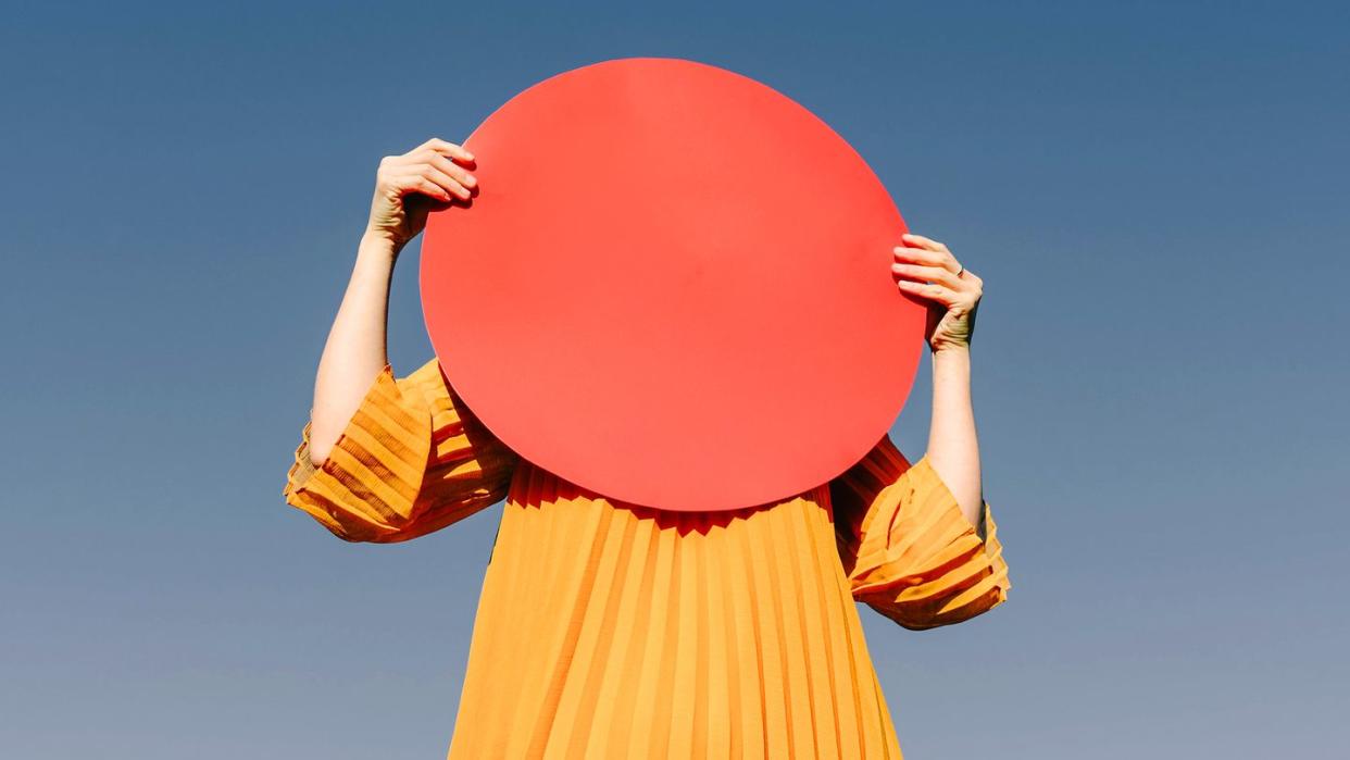 woman holding red circle over her face