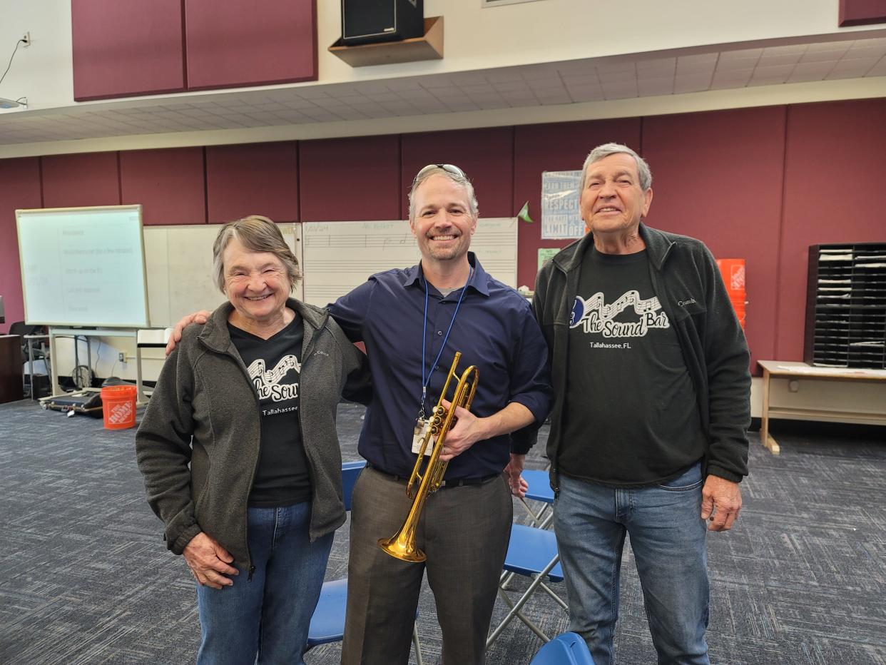 The Sound Bar owners Buddy Levins, right, and his wife, Linda, with the band director at Griffin Middle School when they delivered instruments purchased as a result of the venue's fundraising benefit held in December.