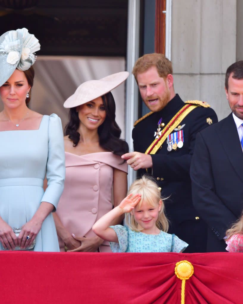 Harry points to the crowd with Meghan.