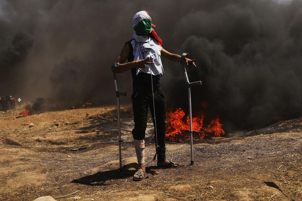 A wounded Palestinian protestor stands at the border fence.&nbsp;