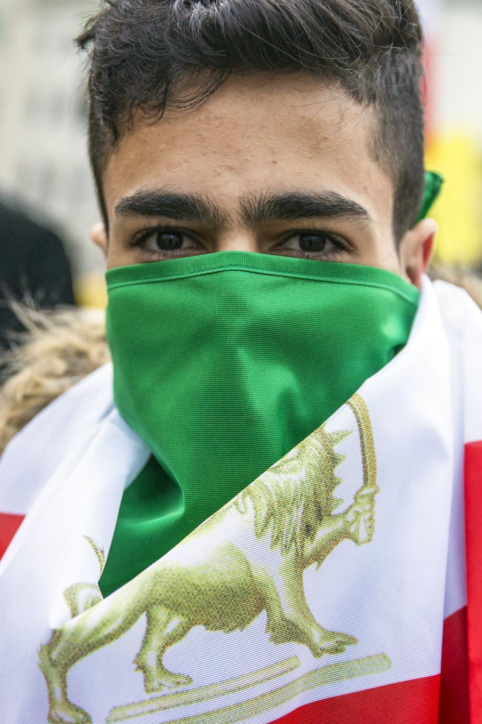 <p>A protester covers his face with the flag of the Iranian consitutional monarchy era as he attends a protest near Brandenburg Gate in Berlin, Germany, Jan. 6, 2018. (Photo: OMER MESSINGER/EPA-EFE/REX/Shutterstock) </p>