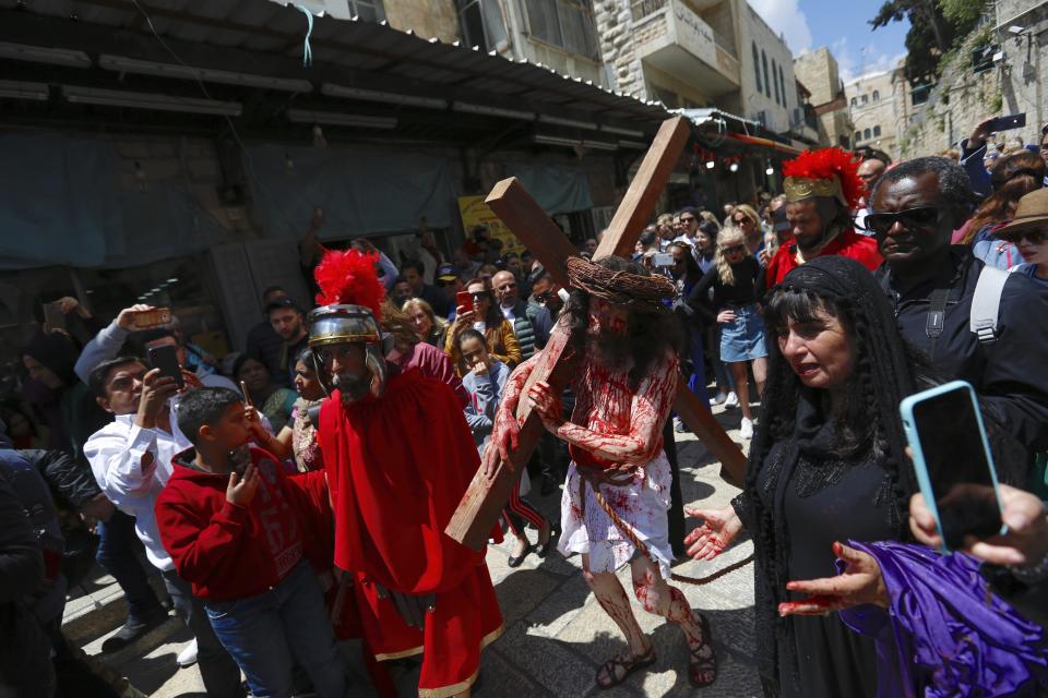 An actor carries a cross toward the Church of the Holy Sepulchre, traditionally believed to be the site of the crucifixion of Jesus Christ, during the Good Friday procession in Jerusalem's old city on April 19, 2019. (Ariel Schalit / ASSOCIATED PRESS)