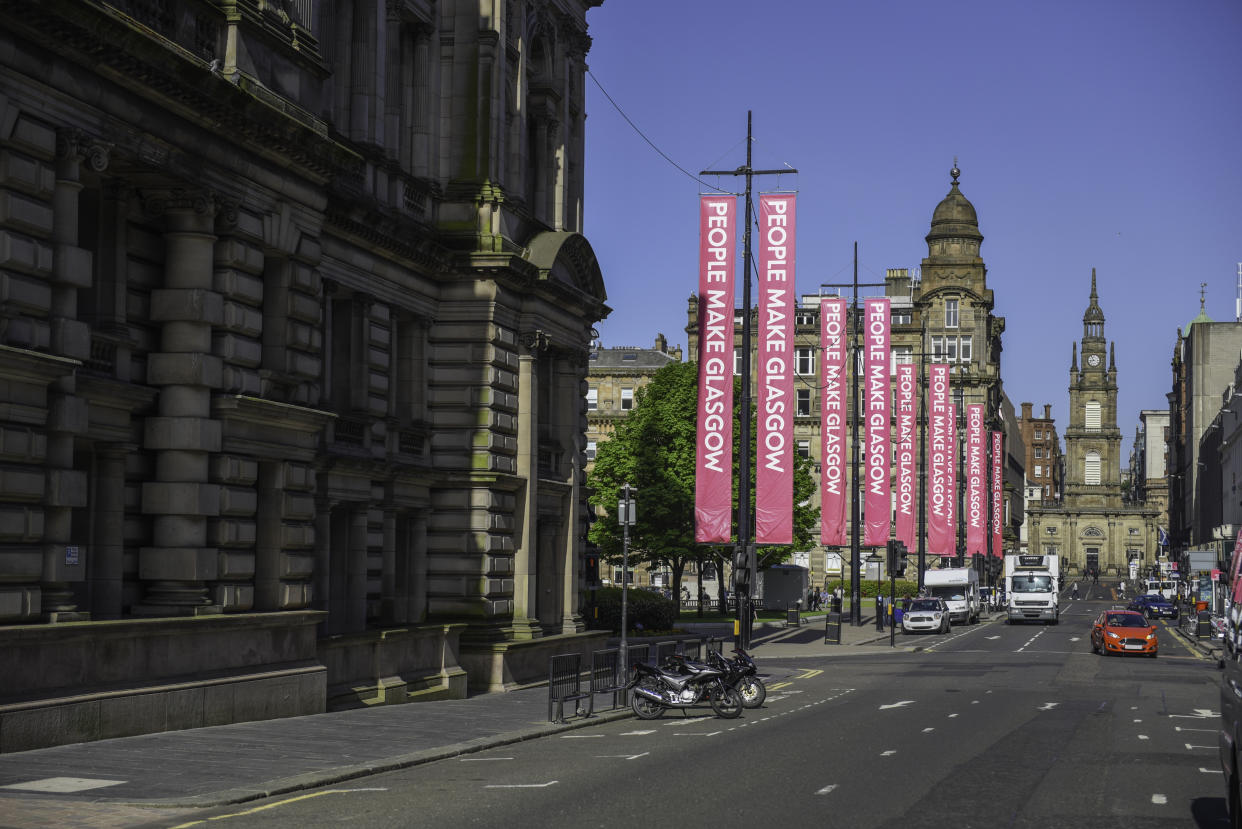 Looking along Glasgow's George street towards George Square and St George's Tron Church (Nelson Mandela Place). People Make Glasgow (the city's brand slogan) banners line George Square.