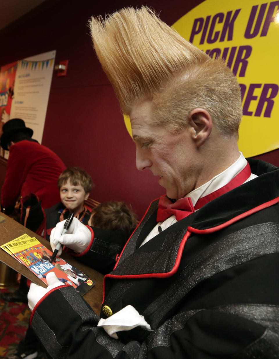 This March 23, 2013 photo shows performer Bello Nock signing autographs in the lobby of the New Victory Theater, after his "Bello Mania" show, in New York. Nock, a seventh-generation circus performer, is never offstage during the 90-minute performance, which combines slapstick clowning with death-defying aerial stunts. He performs through March 31 at the New Victory before moving on to the Canadian side of Niagara Falls and then a 10-week stint at the Beau Rivage Casino in Biloxi, Miss. (AP Photo/Richard Drew)
