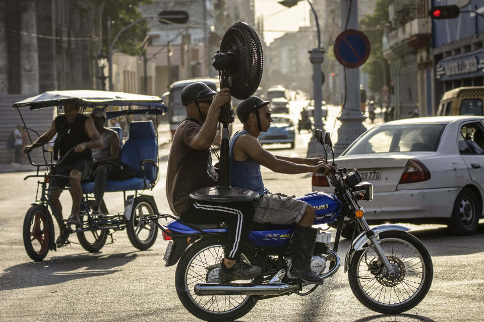 Hombres viajan en motocicleta con un ventilador en La Habana, Cuba, el jueves 6 de abril de 2023. (AP Foto/Ramón Espinosa)