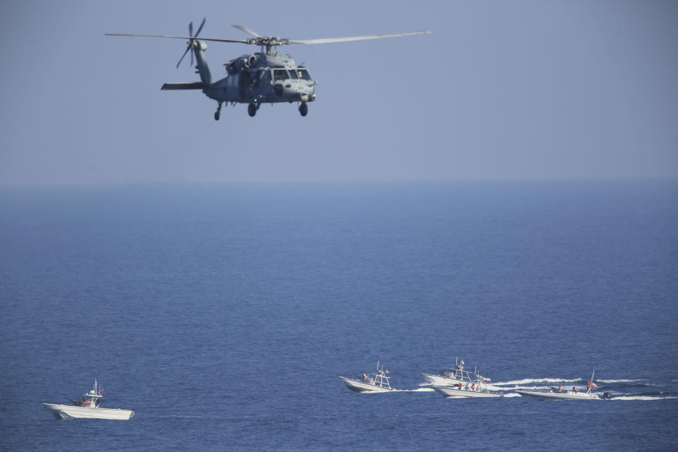 FILE - A U.S. MH-60 Seahawk helicopter flies over Iranian Revolutionary Guard patrol boats in the Strait of Hormuz on Dec. 21, 2018. Thousands of Marines backed by the United States' top fighter jet, warships and other aircraft are slowly building up in the Persian Gulf. It's a sign that while America's wars in the region may be over, its conflict with Iran over its advancing nuclear program only continues to worsen with no solutions in sight. (AP Photo/Jon Gambrell, File)