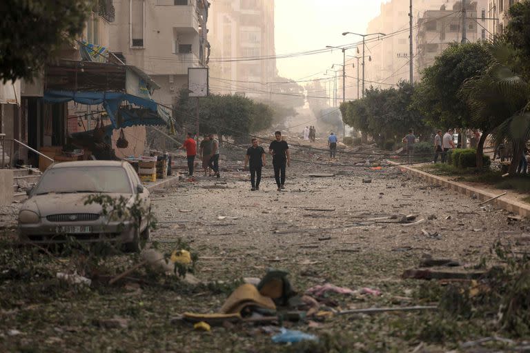 Los palestinos caminan por una calle devastada por los ataques aéreos israelíes en la ciudad de Gaza el 10 de octubre de 2023. 