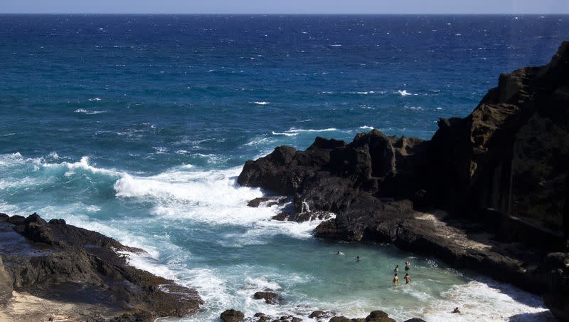 People swim in an alcove as waves crash along the southeast coast of Oahu near Kalaniana’ole Highway. A kayaker off the coast of Oahu was attacked by a large tiger shark.