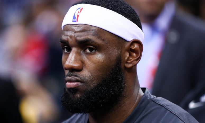 LeBron James sits on the bench during a preseason game.