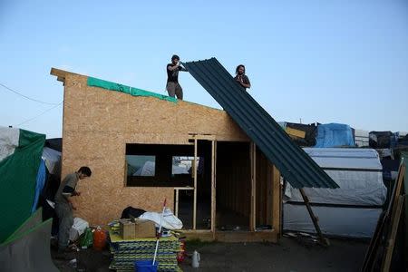 Men remove the roof ing of a makeshift shelter on the second day the evacuation of migrants and their transfer to reception centers in France, as part of the dismantlement of the camp called the "Jungle" in Calais, France, October 25, 2016. REUTERS/Neil Hall