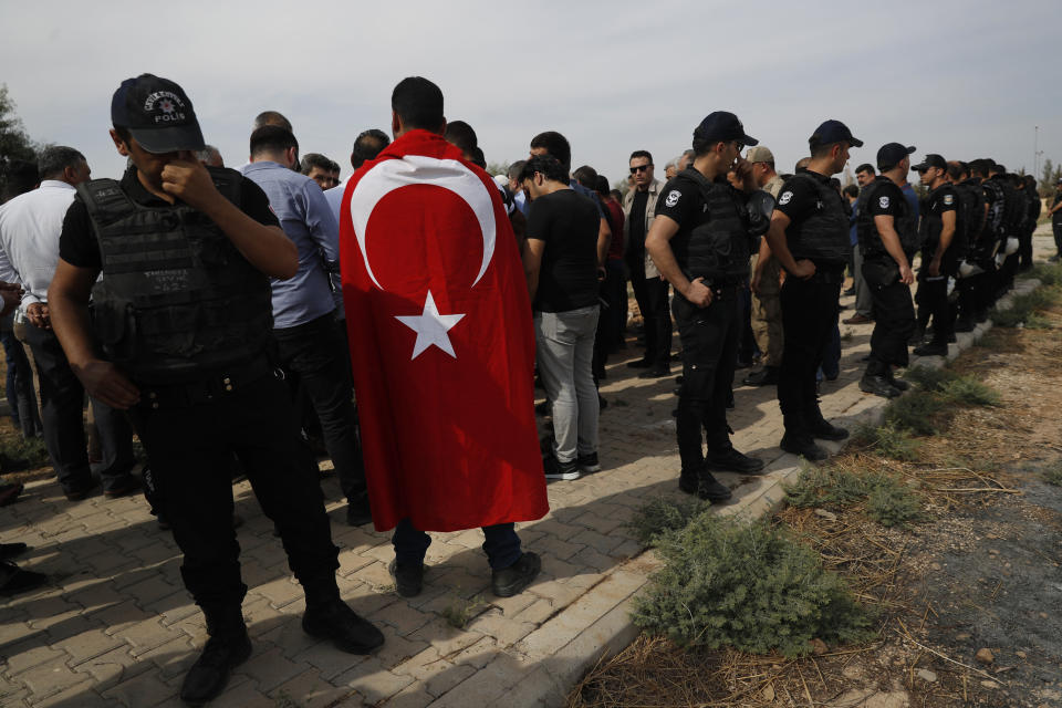 FILE-In this Friday, Oct. 11, 2019 file photo, Turkish police officers secure the area as a Turkish flag-draped mourner attends the funeral of ten-month-old Mohammed Omar Saar, killed during incoming shelling from Syria Thursday, in Akcakale, Sanliurfa province, southeastern Turkey, at the border with Syria. Since Turkey announced its incursion into neighbouring Syria to clear out Kurdish fighters last week, patriotic sentiment has run high with national emblems proudly displayed. (AP Photo/Lefteris Pitarakis, File)