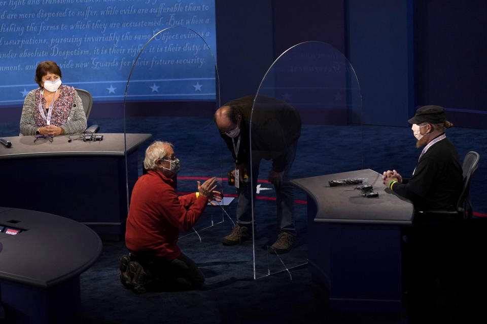 Members of the production crew stand in on the stage near plexiglass barriers which will serve as a way to protect the spread of COVID-19 as preparations take place for the vice presidential debate at the University of Utah, Tuesday, Oct. 6, 2020, in Salt Lake City. The vice presidential debate between Vice President Mike Pence and Democratic vice presidential candidate Sen. Kamala Harris, D-Calif., is scheduled for Oct. 7. (AP Photo/Julio Cortez)