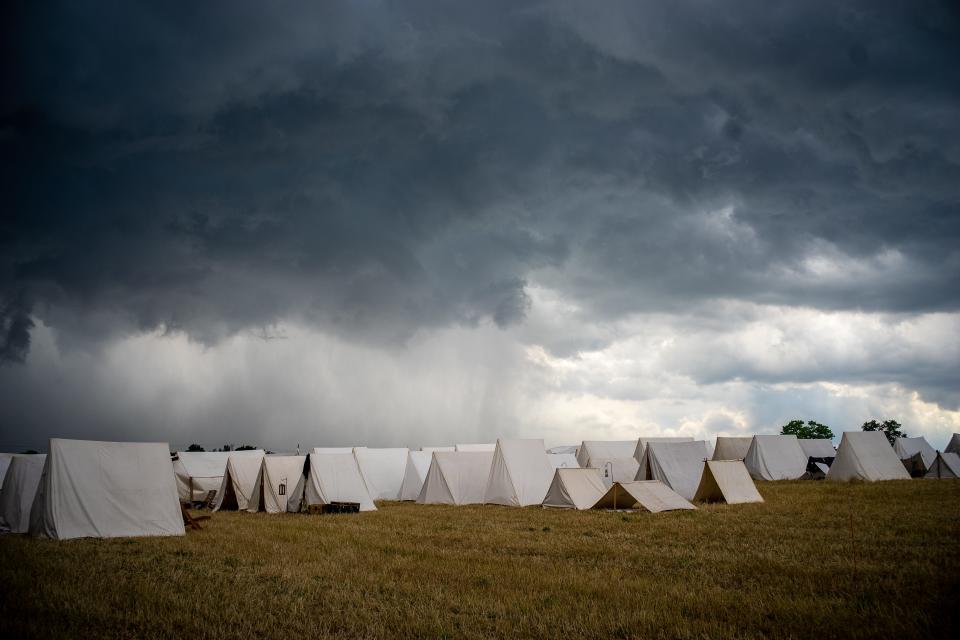 White tents are set up on a flat field.