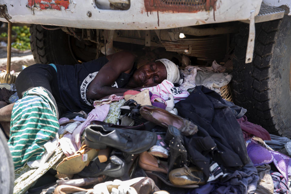 A vendor of used shoes and secondhand clothing sleeps under a truck in Port-au-Prince, Haiti, Saturday, July 10, 2021, three days after President Jovenel Moise was assassinated in his home. (AP Photo/Joseph Odelyn)