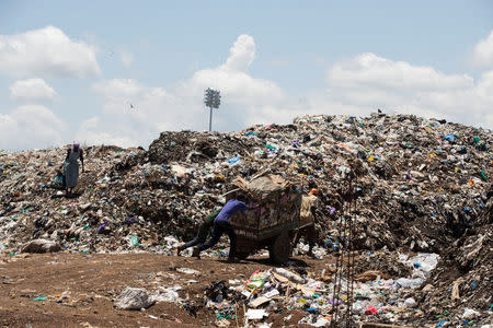 People push a cart into a garbage dump in the city of Kisumu, Kenya April 18, 2017. REUTERS/Baz Ratner