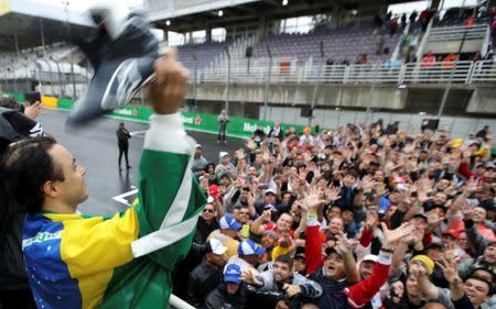 Formula One - F1 - Brazilian Grand Prix - Circuit of Interlagos, Sao Paulo, Brazil - 13/11/2016 - Williams' Felipe Massa of Brazil wears his country's flag over his shoulders as he throws his shoes to fans after the race following his withdrawal due to car problems. REUTERS/Paulo Whitaker