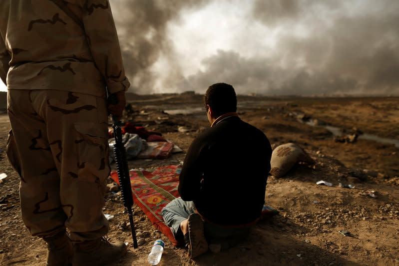 An Iraqi soldier stands next to a detained man accused of being an Islamic State fighter at a check point in Qayyara, south of Mosul, Iraq October 30, 2016. REUTERS/Zohra Bensemra    