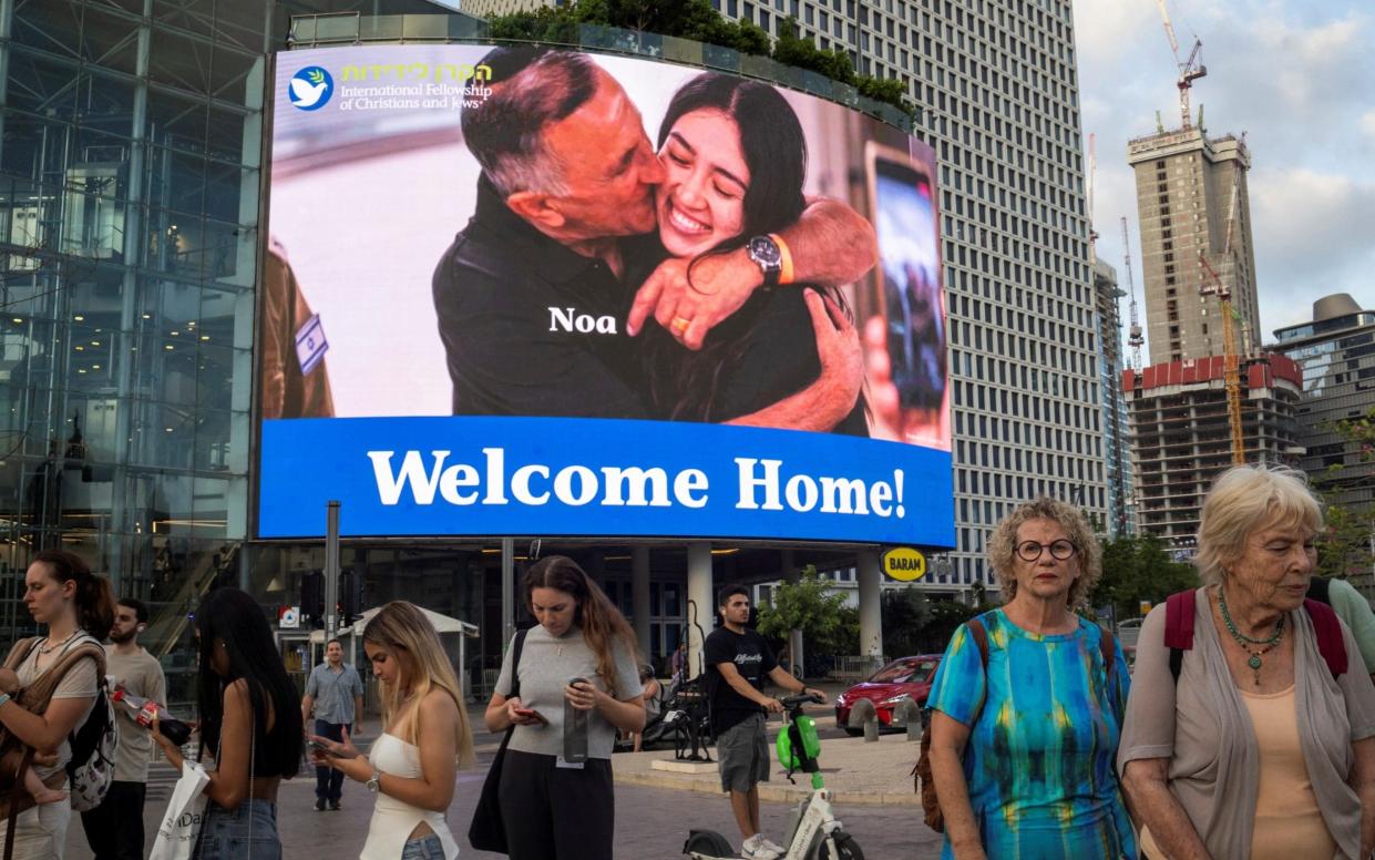 A screen shows Noa Argamani embracing her father after she is rescued from the Gaza Strip