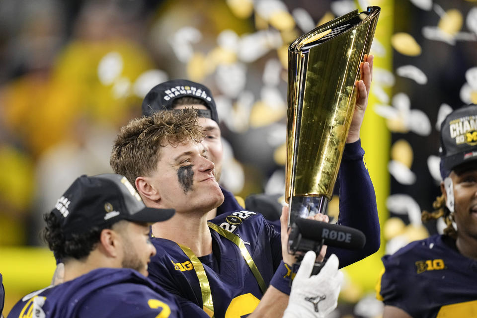 Michigan quarterback J.J. McCarthy celebrates with the trophy after their win against Washington in the national championship NCAA College Football Playoff game Monday, Jan. 8, 2024, in Houston. (AP Photo/Eric Gay)