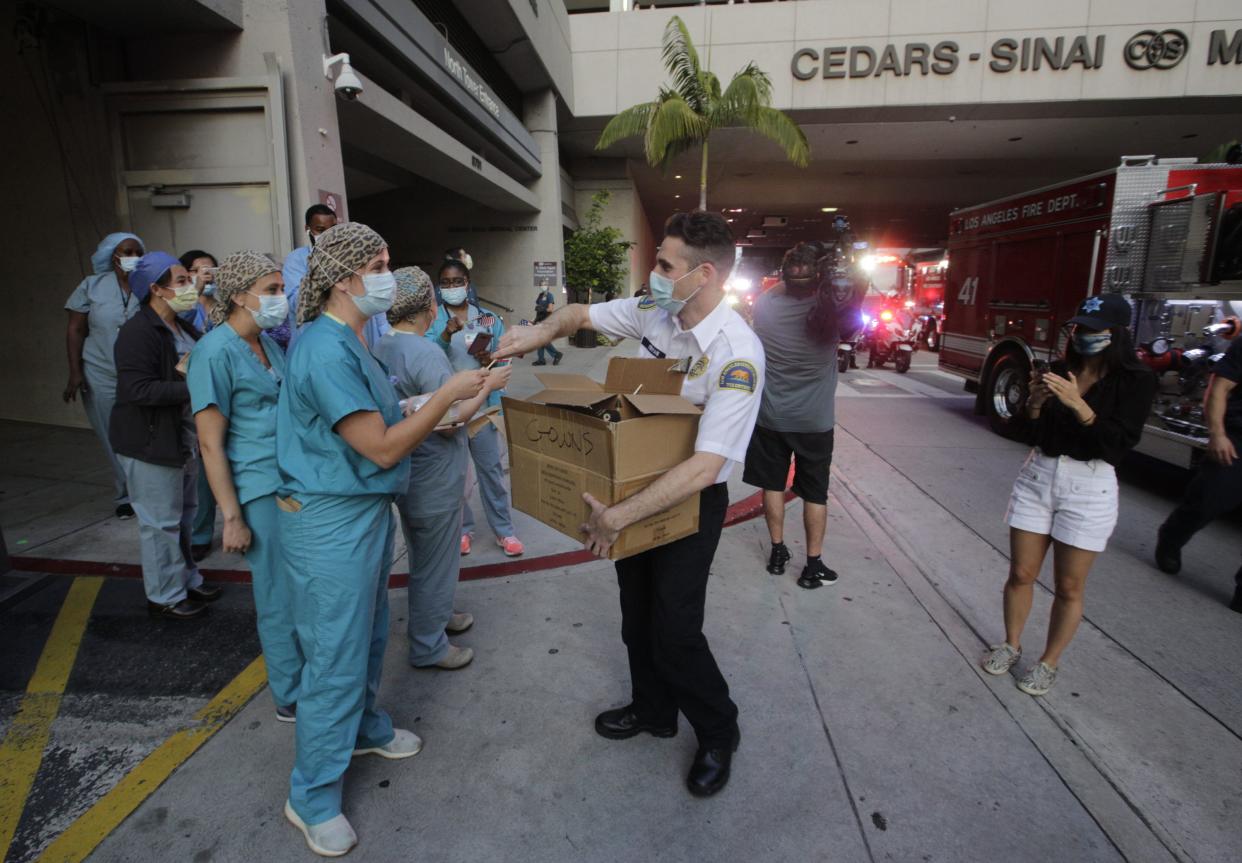 Nurses get flags as police officers, firefighters, sheriff's deputies and first responders parade at Cedars-Sinai Medical Center on Wednesday, May 6, 2020, in West Hollywood, Calif., in a show of support for nurses and health care workers on National Nurses Day.