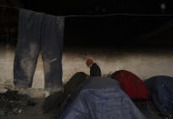 A migrant walks in-between tents while bracing against harsh winter weather inside an abandoned hangar near the Hungarian border, outside of the village of Majdan, Serbia, Tuesday, Jan. 11, 2022. Hungary's nationalist prime minister, Viktor Orban, is keen to use the threat of migrants at his country's southern border to give him an advantage in upcoming elections. But the scale of migration pressure claimed by Orban is drawn into question by statistics from neighboring Serbia and the European Union's border agency. (AP Photo/Bela Szandelszky)