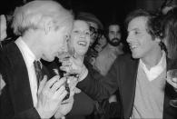 <p>Studio 54's owner, Steve Rubell, offers his friend, artist Andy Warhol, a drink from his glass during an evening of revelry. </p>