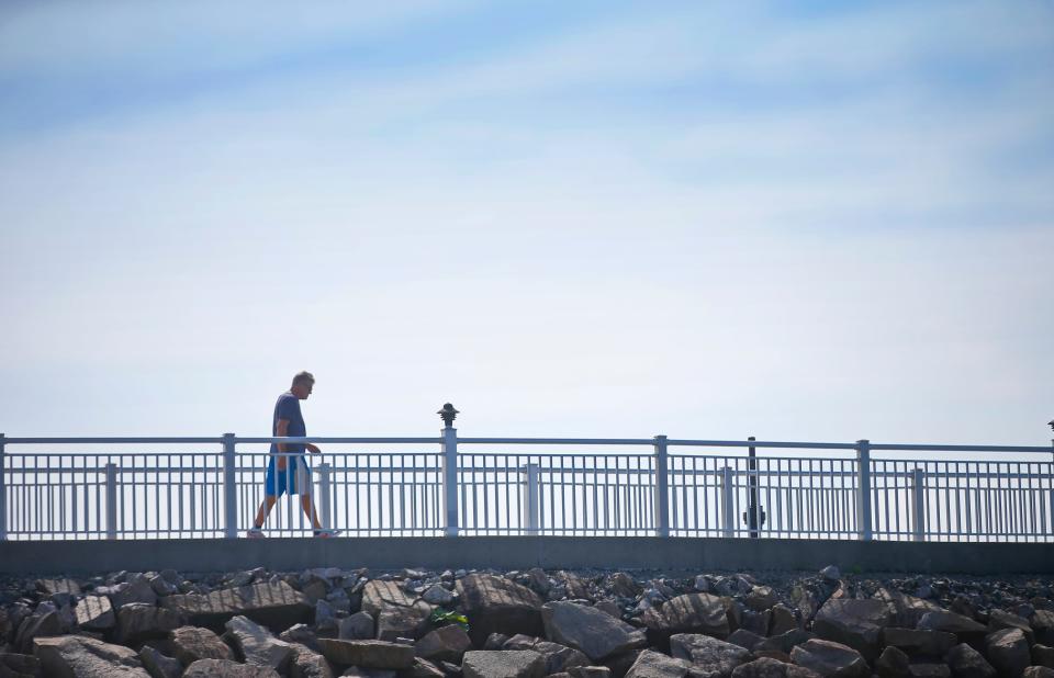 Calm before the storm. A man walks the Blue Lane atop the Hurricane Barrier in New Bedford Thursday, which may close due to the storm expected to hit the region Friday-Saturday.