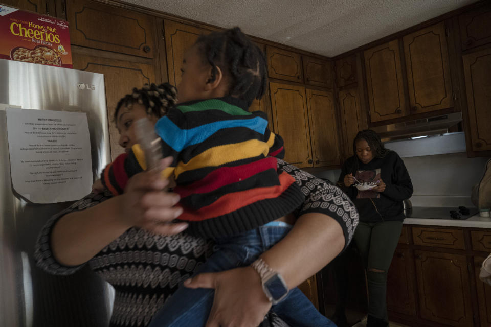 Angelica Lyons carries her son while her younger sister, Ansonia Lyons, finishes a snack in the background, in Birmingham, Ala., on Saturday, Feb. 5, 2022. For Angelica, the day she delivered remains a blur. She would later learn that she nearly died and was placed on a ventilator. (AP Photo/Wong Maye-E)