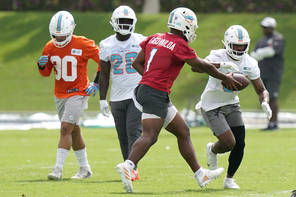 Miami Dolphins quarterback Tua Tagovailoa, left, hands off the ball to running back Raheem Mostert as they takes part in drills at the NFL football team's practice facility, Wednesday, July 27, 2022, in Miami Gardens, Fla. (AP Photo/Lynne Sladky)