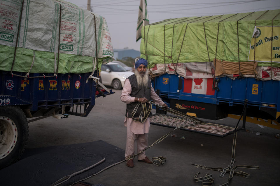 Farmer Satnam Singh, 67, repairs his makeshift cot attached to his tractor trailer parked on a highway during a protest, in the Delhi-Haryana state border, India, Wednesday, Dec. 2, 2020. Instead of cars, the normally busy highway that connects most northern Indian towns to the capital is filled with tens of thousands of protesting farmers, many wearing colorful turbans. The farmers are protesting new laws they say will result in their exploitation by corporations, eventually rendering them landless. (AP Photo/Altaf Qadri)