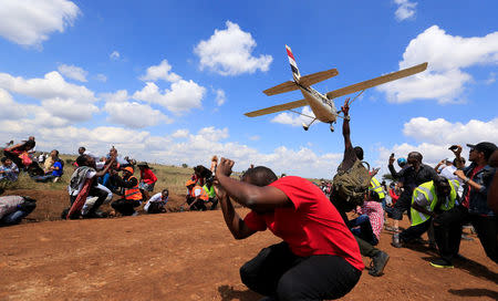 Spectators react as a plane flies over them during the Vintage Air Rally at the Nairobi national park in Kenya's capital Nairobi, November 27, 2016. REUTERS/Thomas Mukoya