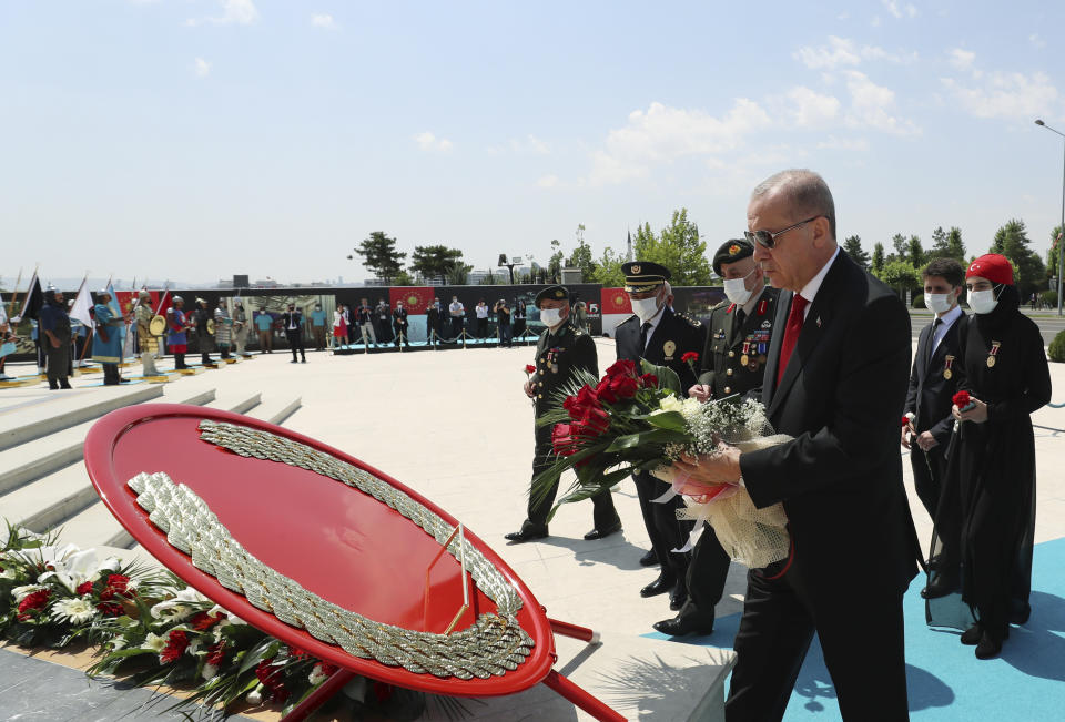 Turkey's President Recep Tayyip Erdogan and family members of coup victims walk to place flowers by the "Martyrs Monument" outside his presidential palace, in Ankara, Turkey, Wednesday, July 15, 2020. Turkey is marking the fourth anniversary of the July 15 failed coup attempt against the government, with prayers and other events remembering its victims. (Turkish Presidency via AP, Pool)