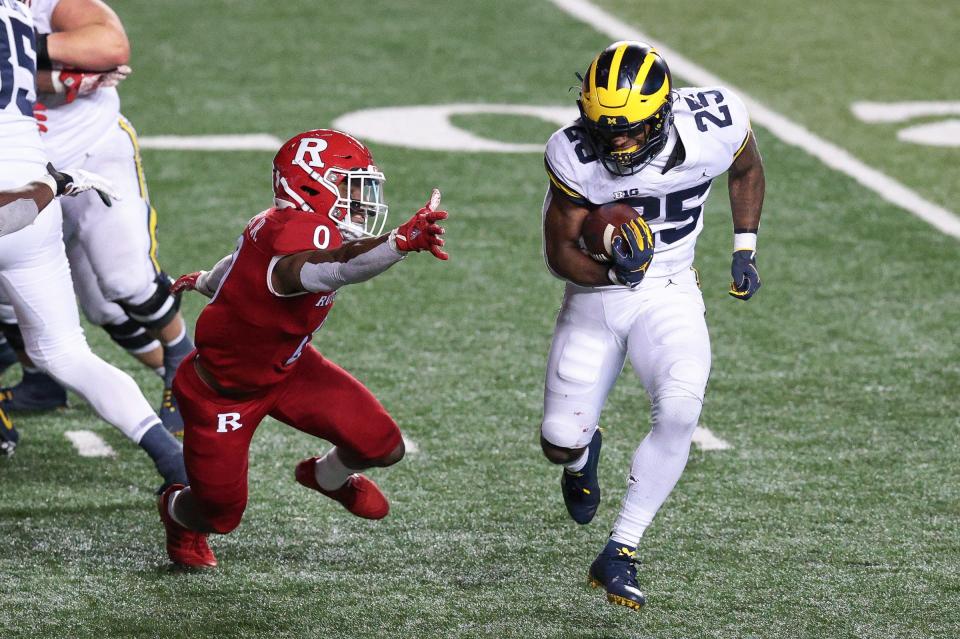 Michigan Wolverines running back Hassan Haskins (25) carries the ball as Rutgers Scarlet Knights defensive back Christian Izien (0)  pursues during overtime at SHI Stadium.
