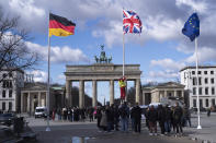 A person raises the Union Jack flag, centre, in front of the Brandenburg Gate at the eve of the visit of King Charles III at the German capital, in Berlin, Tuesday, March 28, 2023. Britain's King Charles III and Camilla, the Queen Consort, will make an official visit to Germany from March 29 to 31, 2023. (AP Photo/Markus Schreiber)