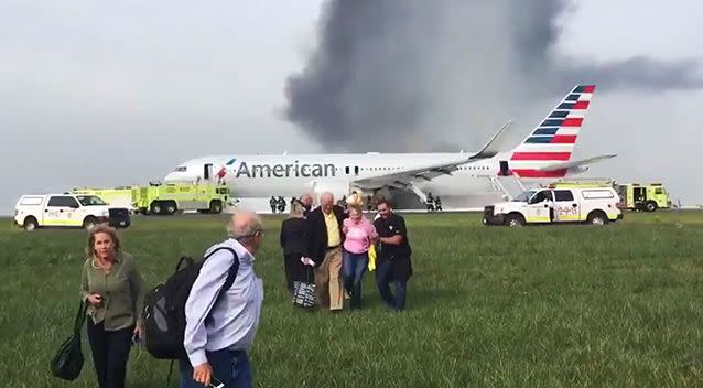 In this photo provided by passenger Jose Castillo, fellow passengers walk away from the burning American Airlines jet. Image: AAP