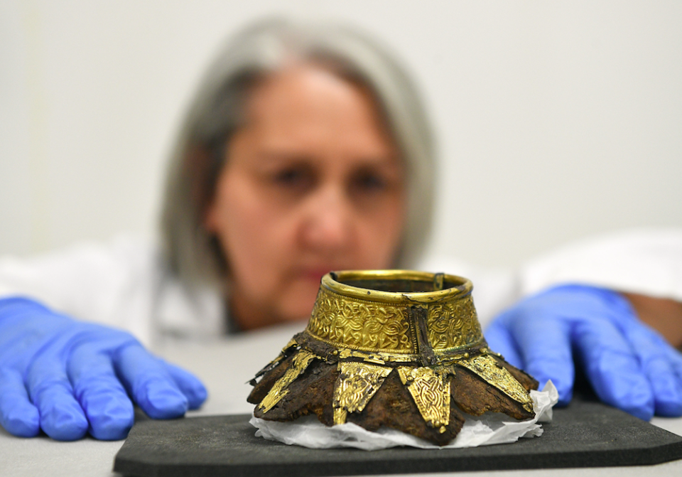 Conservator Claire Reed inspects the remains of a wooden drinking vessel with a decorated gold neck found inside the chamber (PA)