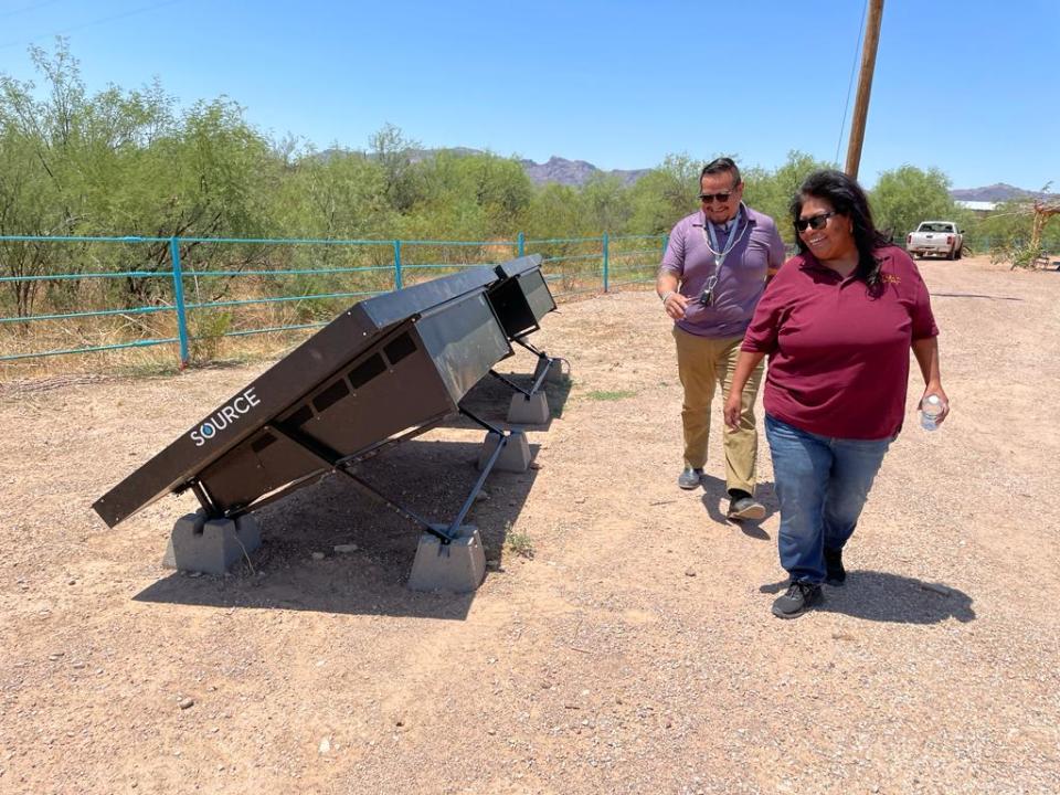 Selina Jesus and Juan Buendia walk by GuVo Store's hydropanels. The solar-powered technology produces about a gallon of water a day from surrounding air.